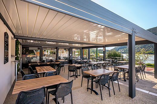 Außenrestaurant-Terrasse mit Tischen und Stühlen auf dem Campingplatz CLICOCHIC Lac du Lit du Roi.