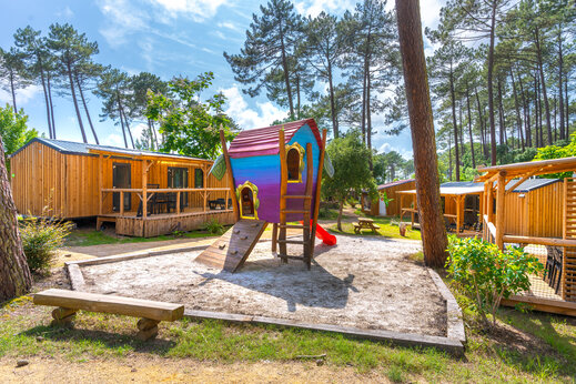 Bunter Spielplatz und Holz-Mobilheime auf dem Campingplatz CAPFUN Landisland in Moliets-et-Maa (40).