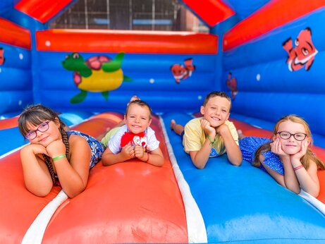 Lächelnde Kinder auf farbenfroher Hüpfburg auf dem Campingplatz CAPFUN Landisland in Moliets-et-Maa (40).