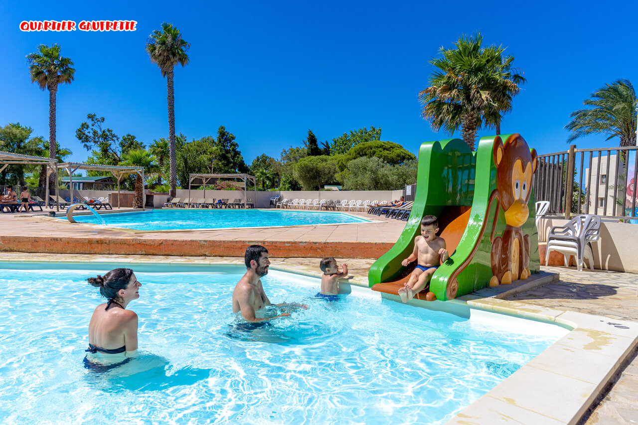 Familienpool mit Kinderrutsche und Palmen auf dem Campingplatz CAPFUN Las Bousigues in Le Barcar�s (66).