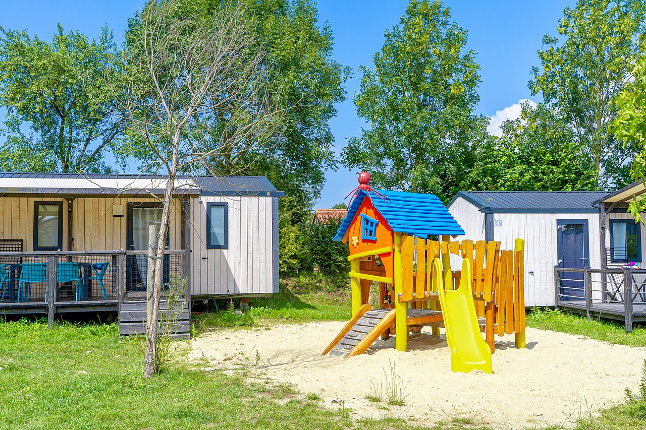 Bunter Kinderspielplatz und moderne Mobilheime auf dem Campingplatz VAGUES OCEANES Les Iles in Hudimesnil (50).