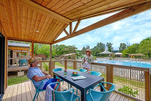 Mobilheim-Terrasse mit Blick auf Pool und Rutschen auf dem Campingplatz CLICOCHIC Les Secrets de Padirac in Padirac (46).
