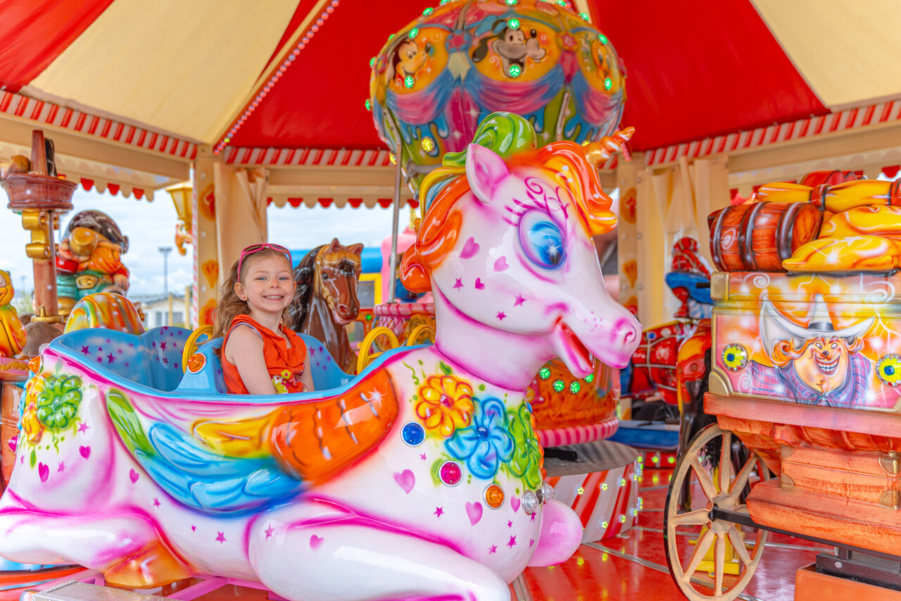 L�chelndes Kind auf Einhorn-Karussell auf dem Campingplatz VAGUES OCEANES Licorne in Dunkerque (59).