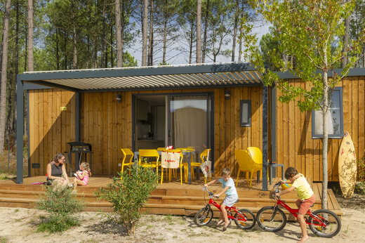 Modernes Mobilheim mit Terrasse, Familie und Kindern beim Radfahren auf Camping CAPFUN Lila in LINXE (40).