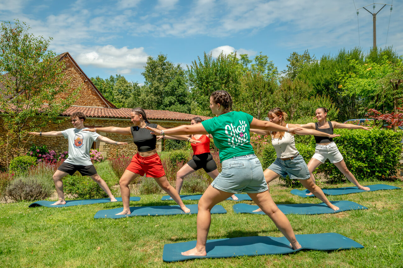 Group of people practicing outdoor yoga at CLICOCHIC Linotte campsite in Le Bugue (24).