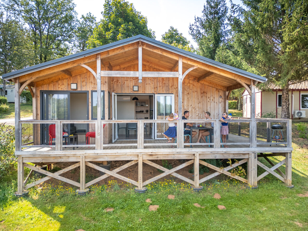 Wooden chalet with terrace and family at CLICOCHIC Linotte campsite, Le Bugue (24).