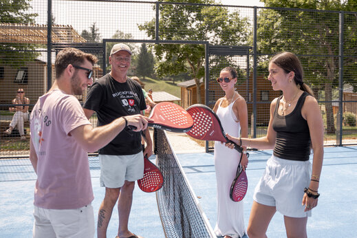 L�chelnde Familie spielt Padel auf dem Multisportplatz des Campingplatzes CLICOCHIC Linotte in Le Bugue (24).
