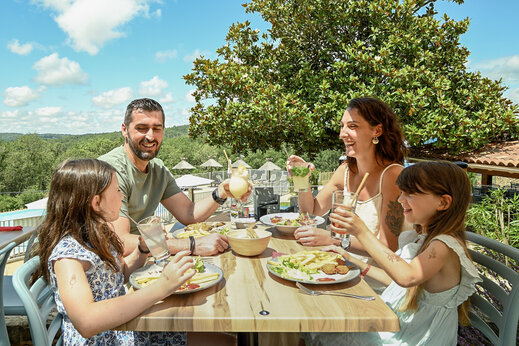 Familie isst im Restaurant des Campingplatzes CLICOCHIC Linotte in Le Bugue (24).
