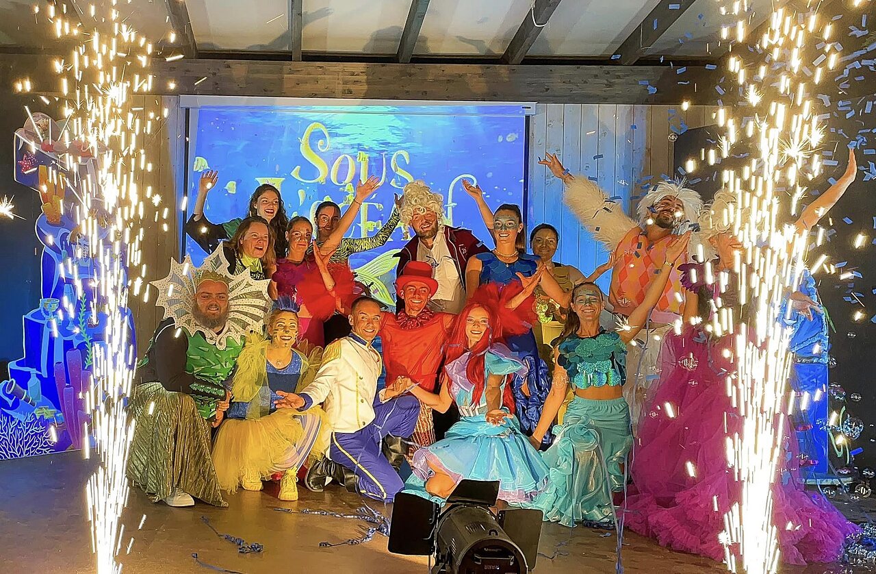 K�nstler in farbenfrohen Kost�men auf der B�hne mit Pyroeffekten auf dem Campingplatz CLICOCHIC Longchamp in Saint Lunaire (35).