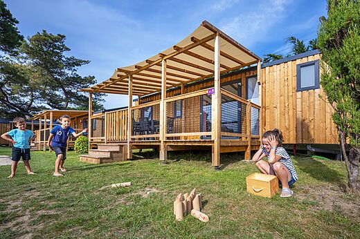 Holz-Mobilheime und spielende Kinder auf dem Campingplatz CLICOCHIC Longchamp in Saint Lunaire (35).