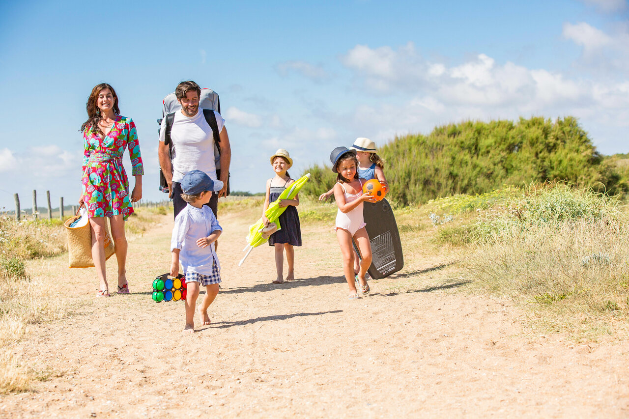 Familie spaziert auf Sandweg mit Strandausr�stung auf dem Campingplatz CAPFUN Loubine in Les Sables d'Olonne (85).