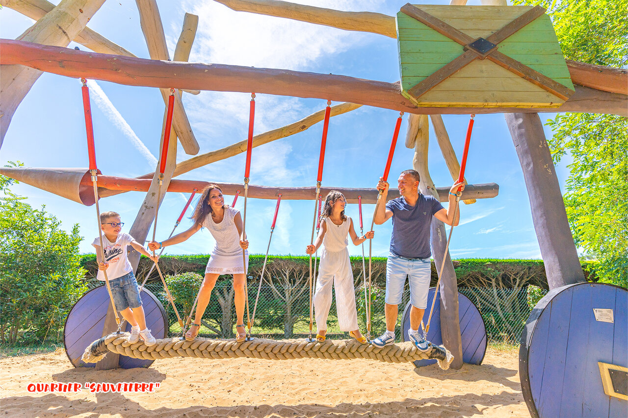 Familie spielt auf gro�er Holzspielstruktur auf Camping CAPFUN Loubine in Les Sables d'Olonne.