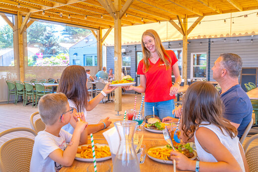 CAPFUN Kellnerin serviert einer Familie Mahlzeiten im Restaurant des Campingplatzes CAPFUN Loubine in Les Sables d'Olonne (85).