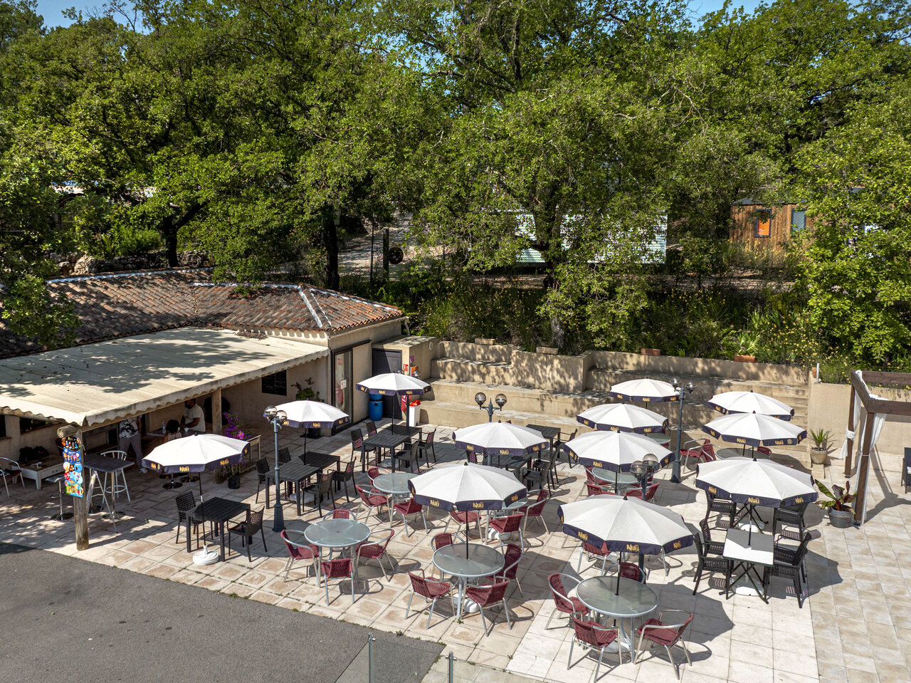 Au�enrestaurant-Terrasse mit Sonnenschirmen und Tischen auf dem Campingplatz CLICOCHIC Lou Cantaire in FAYENCE (83).