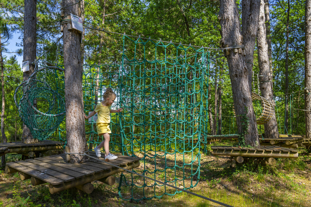 Child on adventure course with suspended nets at CLICOCHIC Lou Castel campsite.