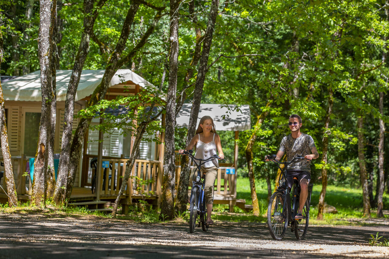 Couple cycling on a path, mobile homes at CLICOCHIC Lou Castel campsite.