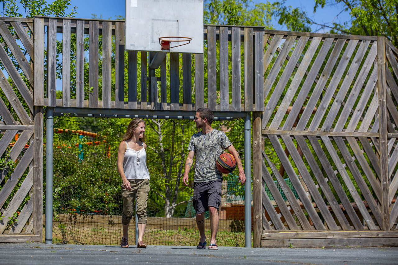 Basketball court with couple at CLICOCHIC Lou Castel campsite, Castelnaud-la-Chapelle (24).