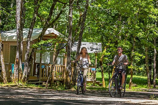 Paar f�hrt Fahrrad auf Waldweg auf Campingplatz CLICOCHIC Lou Castel in Castelnaud-la-Chapelle.