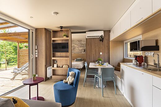 Modern interieur van een stacaravan met woonkamer, keuken en terras op camping CLICOCHIC Lou Castel in Castelnaud-la-Chapelle (24).