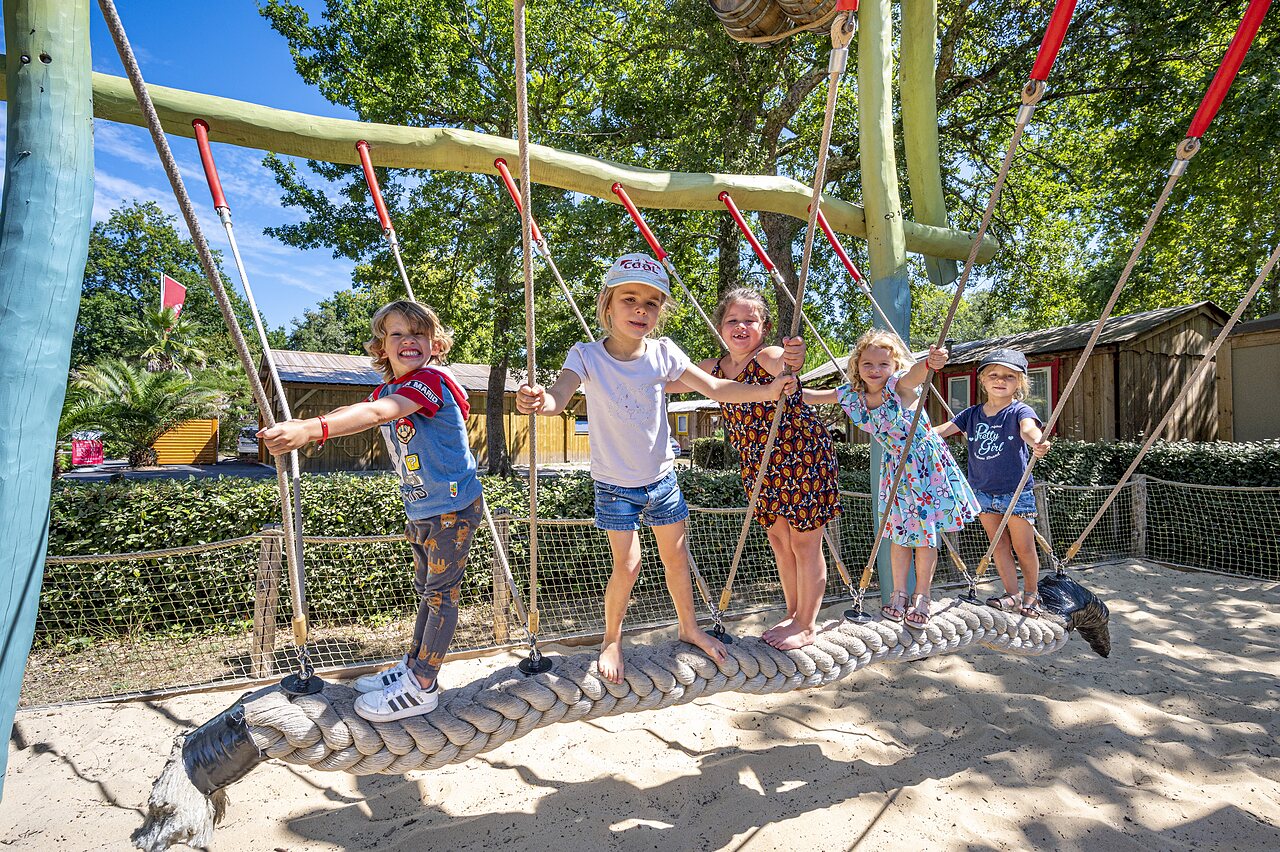 Smiling children playing on rope bridge in playground at CAPFUN Lou Puntaou campsite in LEON (40).