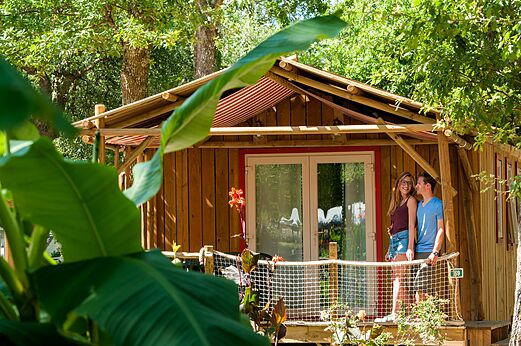 Holz-Mobil-home mit Terrasse und Paar auf Campingplatz CAPFUN Lou Puntaou in LEON (40).