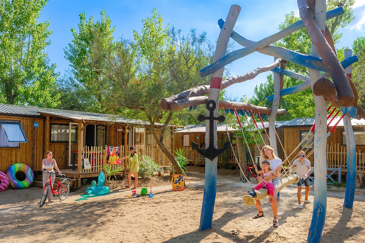 Spielplatz mit Schaukel und Mobilheime auf dem Campingplatz CAPFUN Lou Village in Vendres (34).