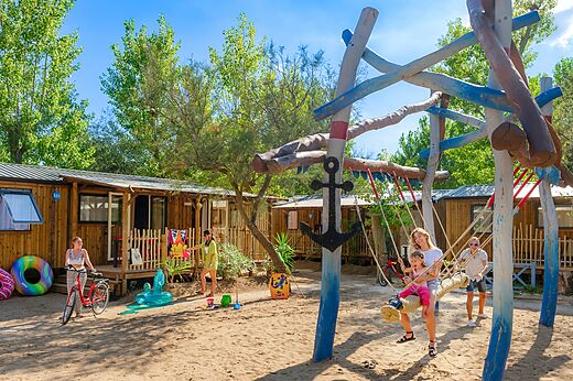 Holzspielplatz, Schaukel, Familie und Mobilheime auf Camping CAPFUN Lou Village.