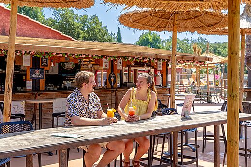 Lächelndes Paar mit Cocktails an der Bar-Restaurant des Campingplatzes CAPFUN Mael in ARGELES SUR MER (66).