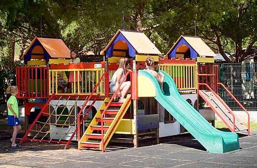 Farbenfroher Spielplatz mit Rutschen und Kindern auf dem Campingplatz VAGUES OCEANES Manoir de Balkos in Valras-Plage (34).