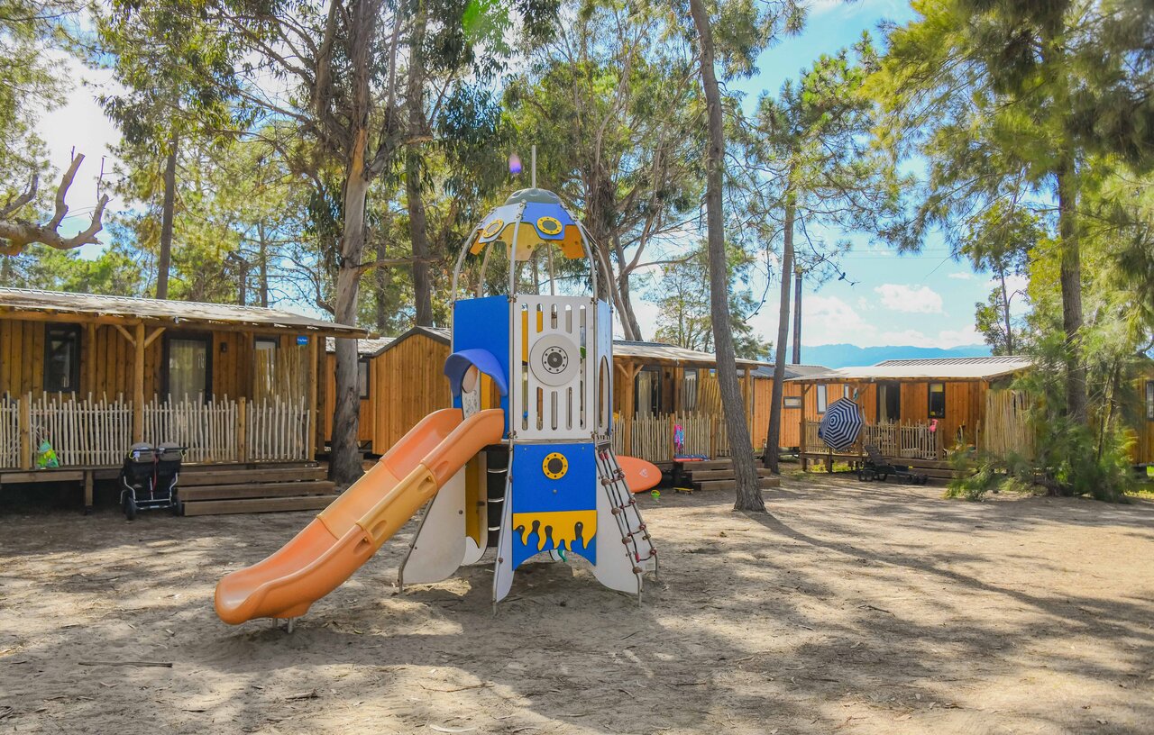 Kinderspielplatz mit Rutsche und Mobilheimen auf dem Campingplatz CAPFUN Marina d'Al�ria in Aleria (20).