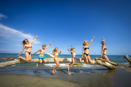 Fr�hliche Familie springt auf Treibholz am Strand auf dem Campingplatz CAPFUN Marina d'Al�ria in Aleria (20).