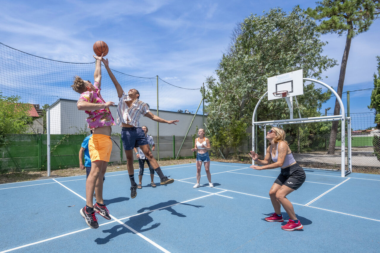 Basketball players on multi-sport court at VAGUES OCEANES Marina Landes campsite in Mimizan (40).