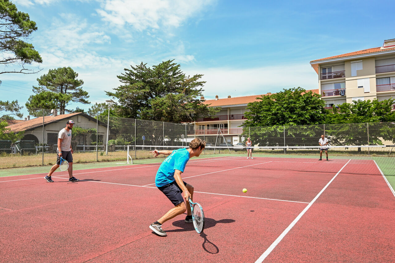 Outdoor tennis court with active players at VAGUES OCEANES Marina Landes campsite in Mimizan (40).