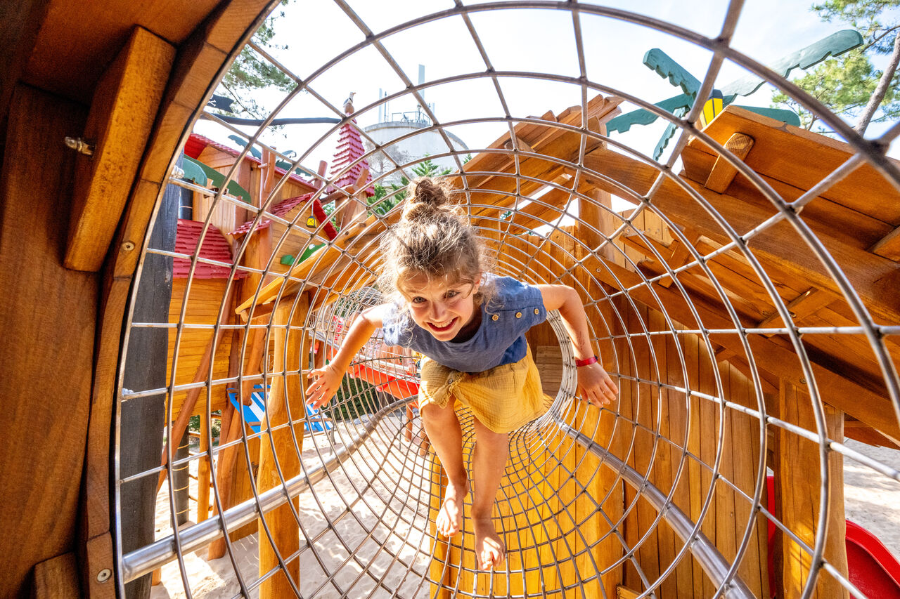 Smiling child in play tunnel at VAGUES OCEANES Marina Landes campsite, Mimizan.