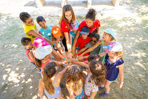 Kinder und Animateure im Kreis, Hände zusammen für Gruppenaktivität auf dem Campingplatz VAGUES OCEANES Marina Landes in Mimizan (40).