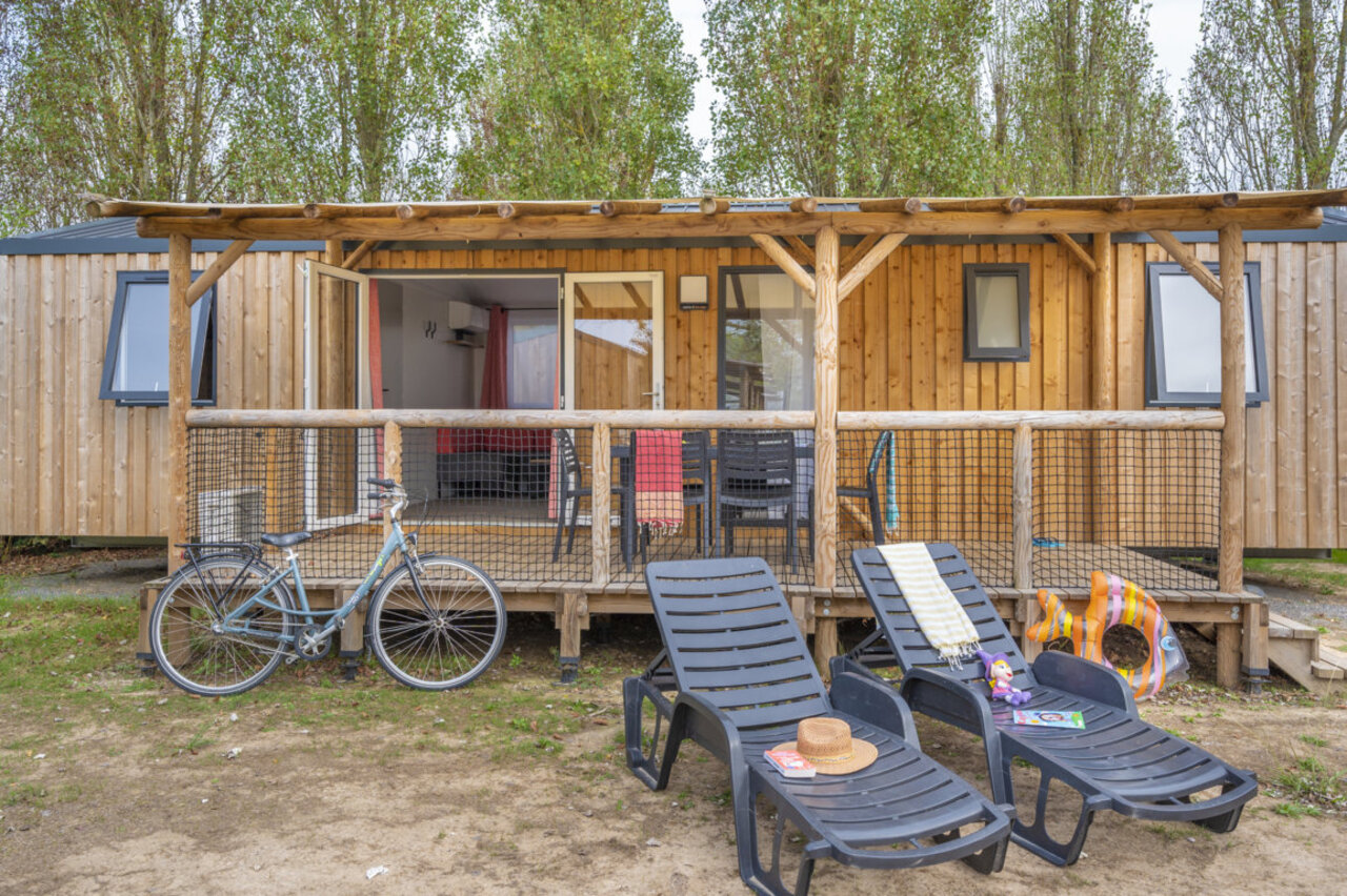 Wooden mobile home, furnished terrace, sun loungers, bike at CLICOCHIC M�doc Bleu campsite.