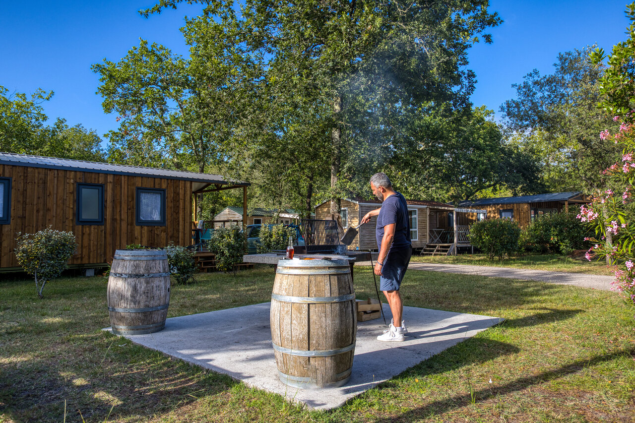 Man grilling barbecue near Mobile homes, CLICOCHIC M�doc Bleu campsite Carcans (33).