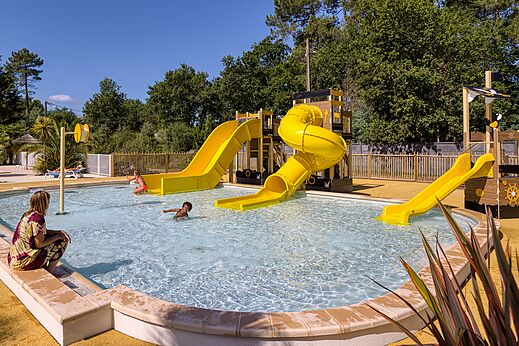 Schwimmbad mit gelben Wasserrutschen auf dem Campingplatz CLICOCHIC Médoc Bleu in Carcans (33).