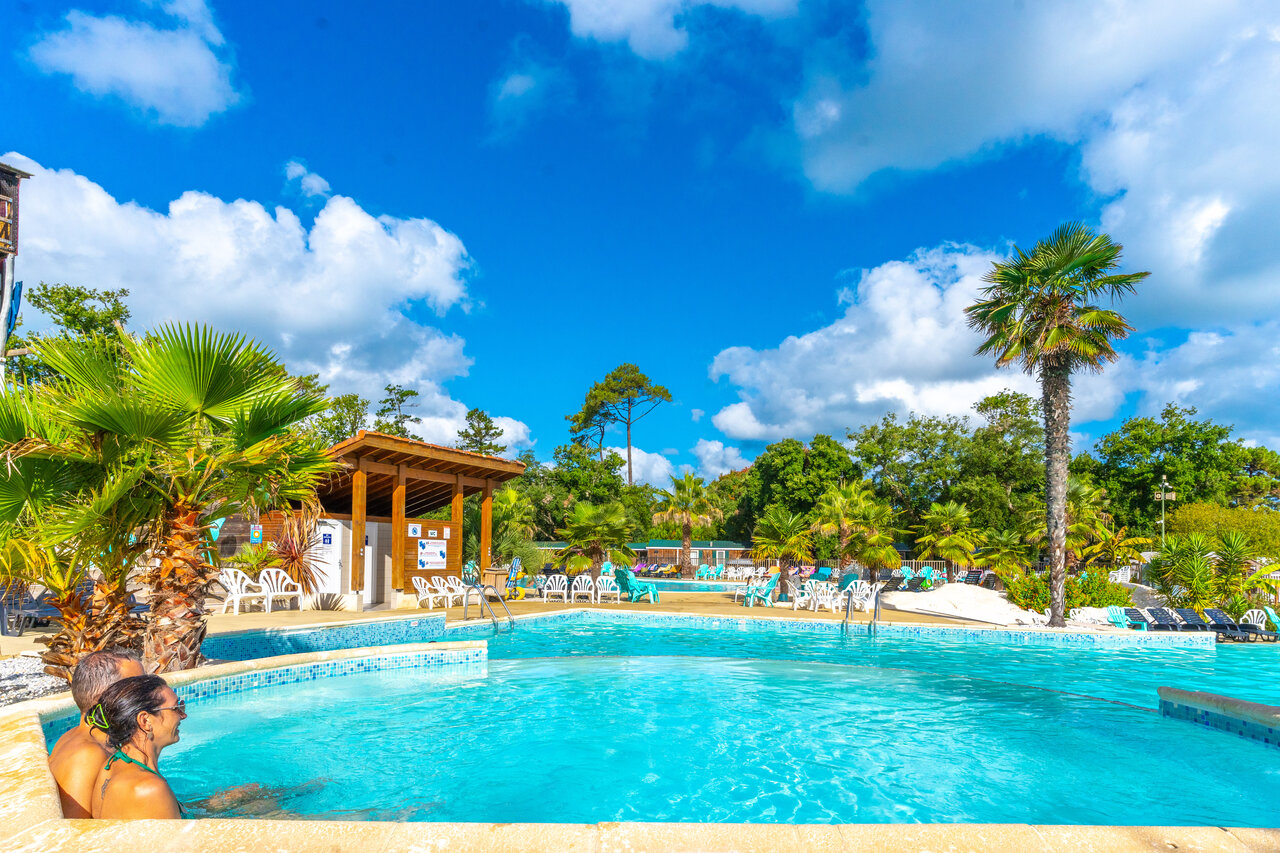 Outdoor pool, couple, palm trees at CAPFUN Mer campsite in Labenne-Oc�an (40).