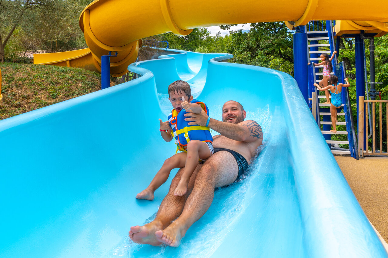 Vader en kind op reuzenglijbaan waterpark bij camping CAPFUN Merle Roux in Baix (07).