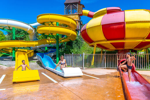 Große, bunte Wasserrutschen mit Kindern auf dem Campingplatz CAPFUN Merle Roux (07).