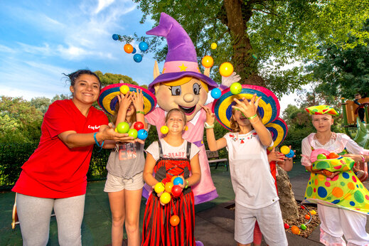 Animateurin, Kinder und Capfun Maskottchen spielen mit Bällen auf dem Campingplatz CAPFUN Merle Roux in Baix (07).