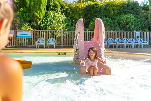 Mädchen auf Wasserrutsche im Kinderbecken auf Camping CAPFUN Merle Roux in Baix (07).