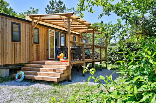 Holz-Mobilheim mit überdachter Terrasse und Gartenmöbeln auf dem Campingplatz CAPFUN Merle Roux in Baix (07).