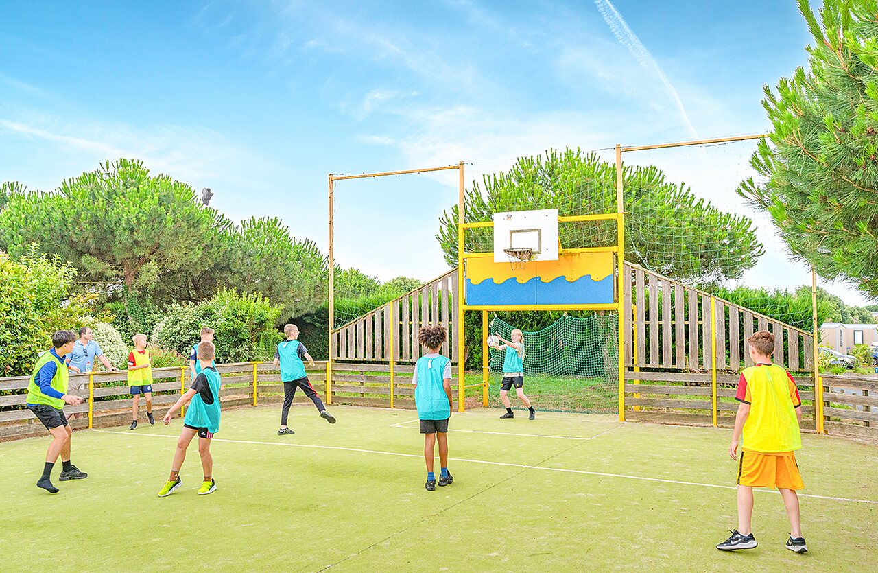 Kinder spielen Basketball auf Multisportplatz auf Camping VAGUES OCEANES in Givrand.