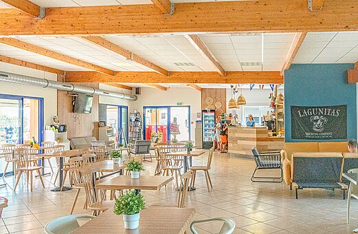 Moderner Bar- und Restaurantbereich mit Tischen und Stühlen auf dem Campingplatz VAGUES OCEANES Michelière in Givrand (85).