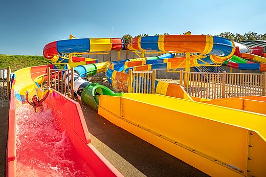 Bunte Wasserrutschen mit Kind beim Spaß auf Camping CAPFUN Mirabelle in VOLSTROFF (57).