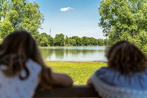 Ruhiger See umgeben von grünen Bäumen am Campingplatz CAPFUN Mirabelle in VOLSTROFF (57).