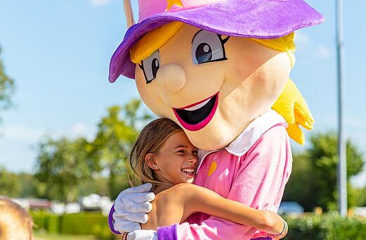 Campingmaskottchen und l�chelndes Kind umarmen sich, Animation auf dem Campingplatz CAPFUN Montsabert in COUTURES (49).