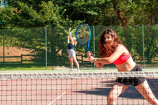 Deux jeunes femmes jouent au tennis sur le court au camping CAPFUN Moulinal à BIRON (24).